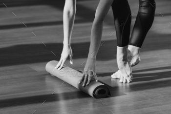 cropped black and white shot of young woman rolling out yoga mat / Photodune, Misc