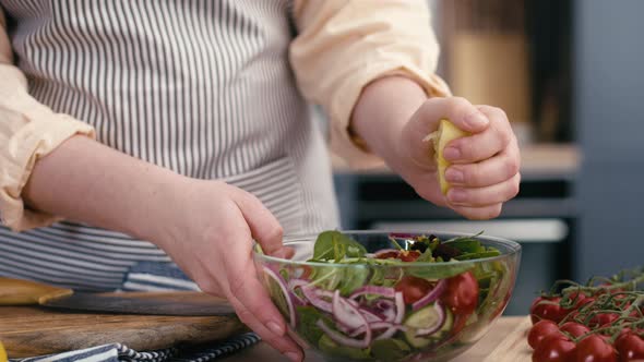 Close up of woman squeeze lemon for salad. Shot with RED helium camera in 4K.