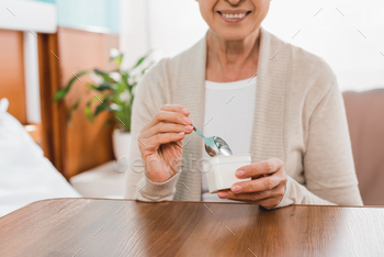 cropped shot of smiling senior woman eating yogurt in hospital / Photodune, Misc