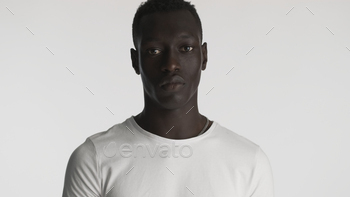 African American guy wearing white t-shirt posing on camera with serious look over white background / Photodune, Misc