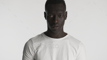Angry African American guy wearing t-shirt  looking aggressive on camera with over white background / Photodune, Misc