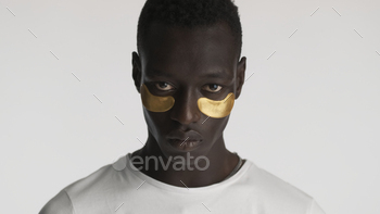 Portrait of handsome African American man with gold eye patches looking serious on camera isolated / Photodune, Misc