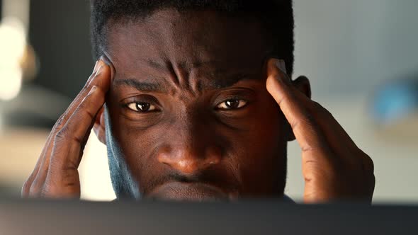 Portrait of a young man with a headache at a laptop during working hours in the office