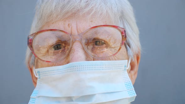 Portrait of Granny in Glasses Wears Protective Mask From Virus. Grandma Looks Into Camera with