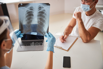 Responsible medic checking x-ray image while tending to patient