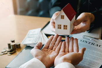 Home agents are giving house gifts to new home buyers in office room. / Photodune, Misc