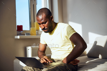 Anxious worker sitting on a bed edge with a computer