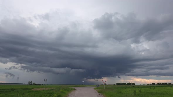 Dramatic Sky With Rain Clouds On Horizon Above Rural Landscape Country Road Through Field