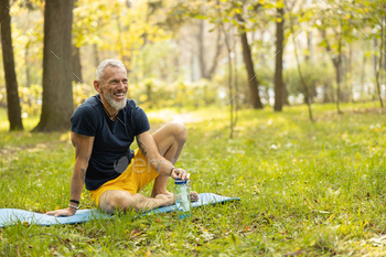 Jolly sporty male doing workout on mat in nature / Photodune, Misc