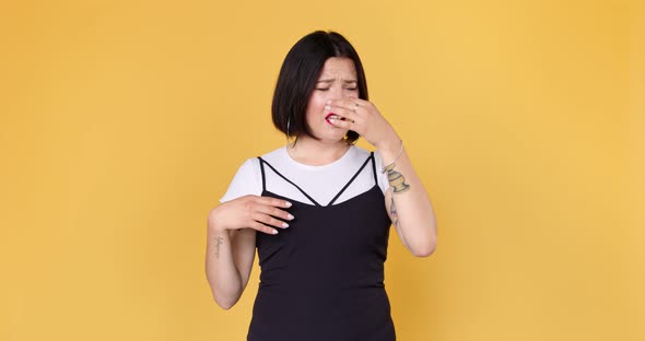 Repulsion to bad smell. Unhappy woman with tattoo squeezing nose with fingers