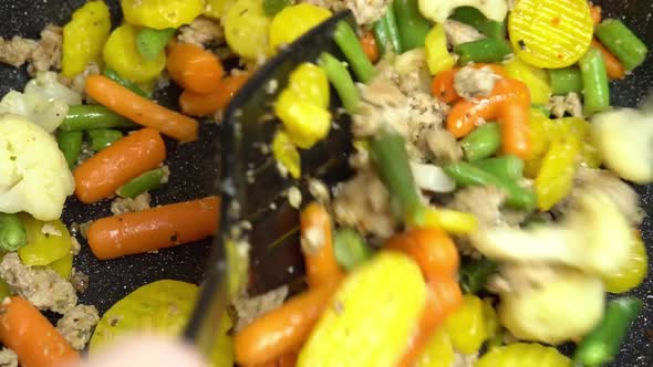 Close up view of steaming frying pan and mixed vegetables with frying minced