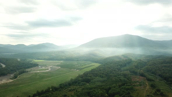 Aerial View of Sunset with Fog Above Forest and Mountains. Morning Foggy Smoke in Magic Rays Light