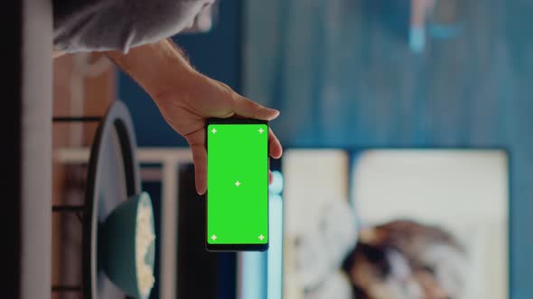 Vertical Video Young Man Watching Horizontal Green Screen on Smartphone