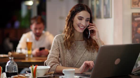 Female Freelancer Works Outside the Home Female Developer Sits at the Bar and Works at a Laptop