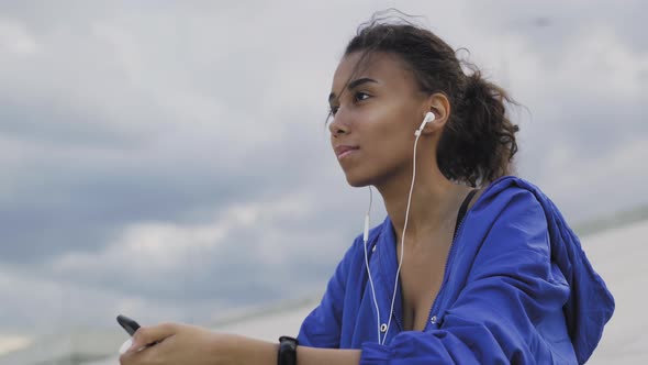 Woman Wearing Sportswear, Listening Music From Mobile Phone with Headphone, Between Exercise in a