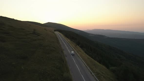 Drone Follows Car Through Green Hills at Sunset