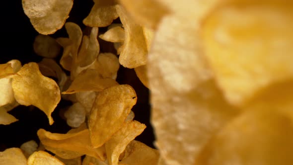 Super Slow Motion Detail Shot of Potato Chips Falling on Black Background at 1000Fps