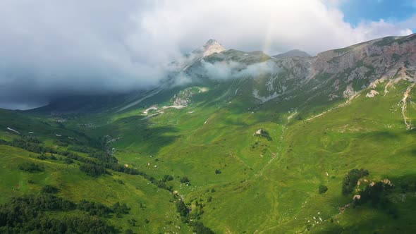 Aerial View of Valley of Stunning Snow Mountains with Dense Wild Forests, Grass Under Flying Steam