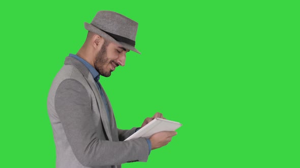 Casual Man Using Tablet and Smiling While Waking on a Green Screen, Chroma Key.