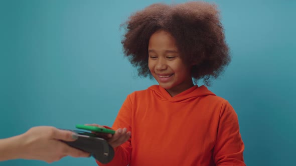 African American girl paying with mobile phone and contactless terminal