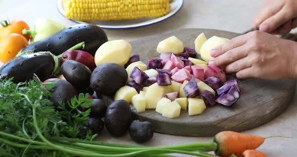 A woman is cooking vegetables in a kitchen, cut colors  potatoes