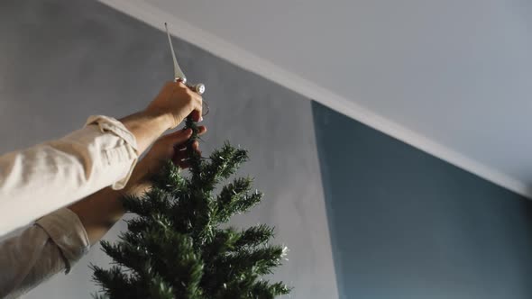 Man Decorating Christmas Tree with Red Toy