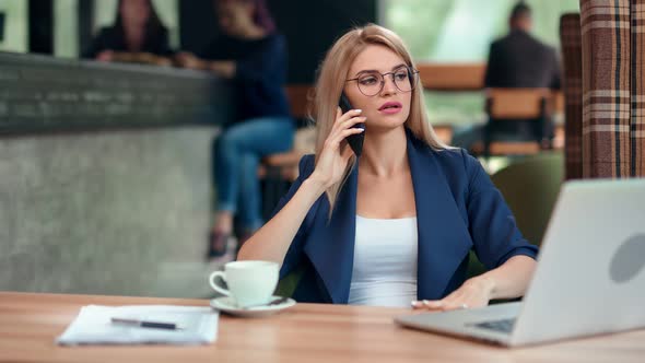 Confident Stylish Business Female Talking Using Smartphone Sitting on Table in Cafe