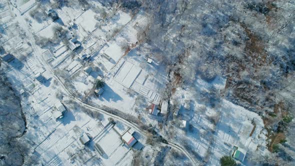 Aerial Tilt View of a Winter Village Mountains and a Frozen Forest with Snow and Ice Covered Trees
