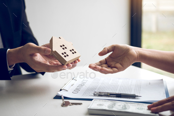 giving house model to client in the agency office.
