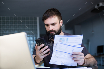 文書を見てテーブルに座っているひげを生やした若い男 / Photodune, Misc