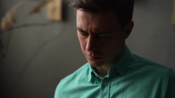 Closeup Face of Concentrated Young Man Reading Interesting Book Sitting in Chair in Dark Library