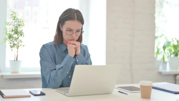 Young Woman Working on Laptop and Thinking at Work