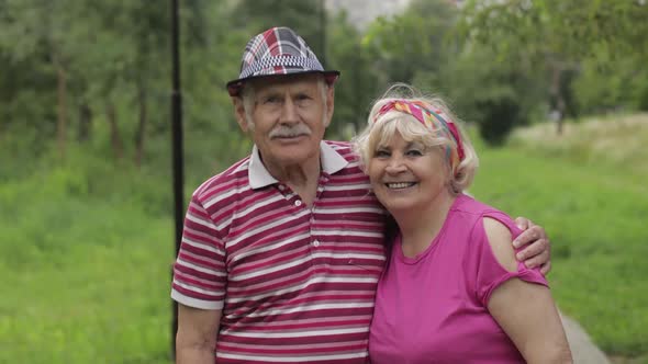 Senior Caucasian Couple Walking in Park Embracing. Elderly Man Walks with Woman. Husband, Wife