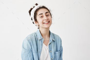 Dark-haired young female model wearing do-rag and denim shirt, looks aside with dreamful and joyful / Photodune, Misc