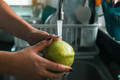 Woman hand is holding a guava and washing with water at the tap in the kitchen at home. - PhotoDune Item for Sale