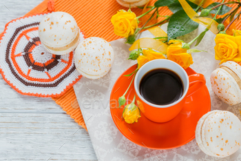 Orange cup of black coffee, yellow roses flowers and sweet pastel french macaroons / Photodune, Misc