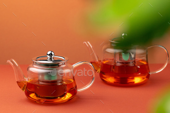 Glass teapot with black tea on background of blurred foliage / Photodune, Misc