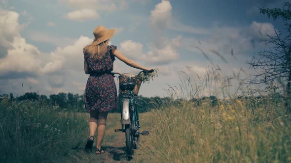 Woman In Hat Enjoying Weekend.Woman Cyclist Walking With Bike On Holiday Vacation Trip. Wildflower.