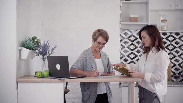 Mature and Middle-aged Woman Reading and Writing at Home