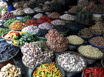 ler in the middle of a large assortment of row loose vegetables and fruits for sale in a street. Short circuit production