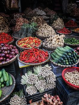 ler in the middle of a large assortment of row loose vegetables and fruits for sale in a street. Short circuit production