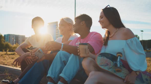 Happy Smiling Teenage Friends Laughing Outside at Something in Smartphone or Mobile Phone