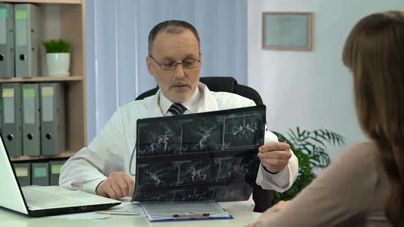 Doctor Looking at Blood Vessels X-Ray, Talking to Patient About Diagnosis