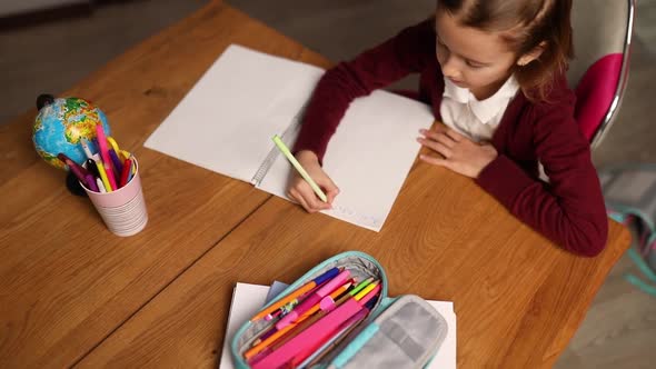 Focused schoolgirl sit at desk doing homework handwriting