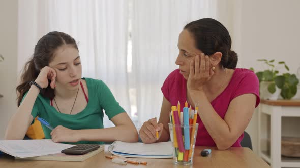 Mother helping her teenage daughter prepare homework