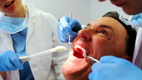Dentists examining a male patient with tools