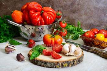 Ripe juicy tomatoes of different varieties, green fragrant basil, garlic on the table / Photodune, Misc