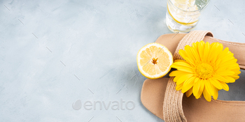 Summer fashion concept with straw sandals on turquoise background with yellow flowers and lemons / Photodune, Misc