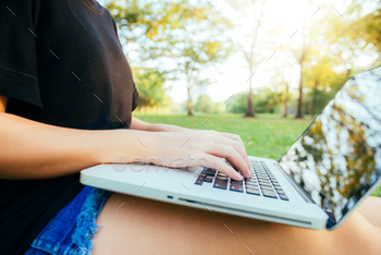 Young asian woman's legs on the green grass with open laptop. / Photodune, Misc