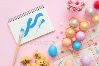 easter egg painted in pastel colors composition and spring flowers with paint brush notebook. / Photodune, Misc